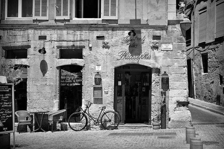 a black and white photo of a bike parked in front of a building
