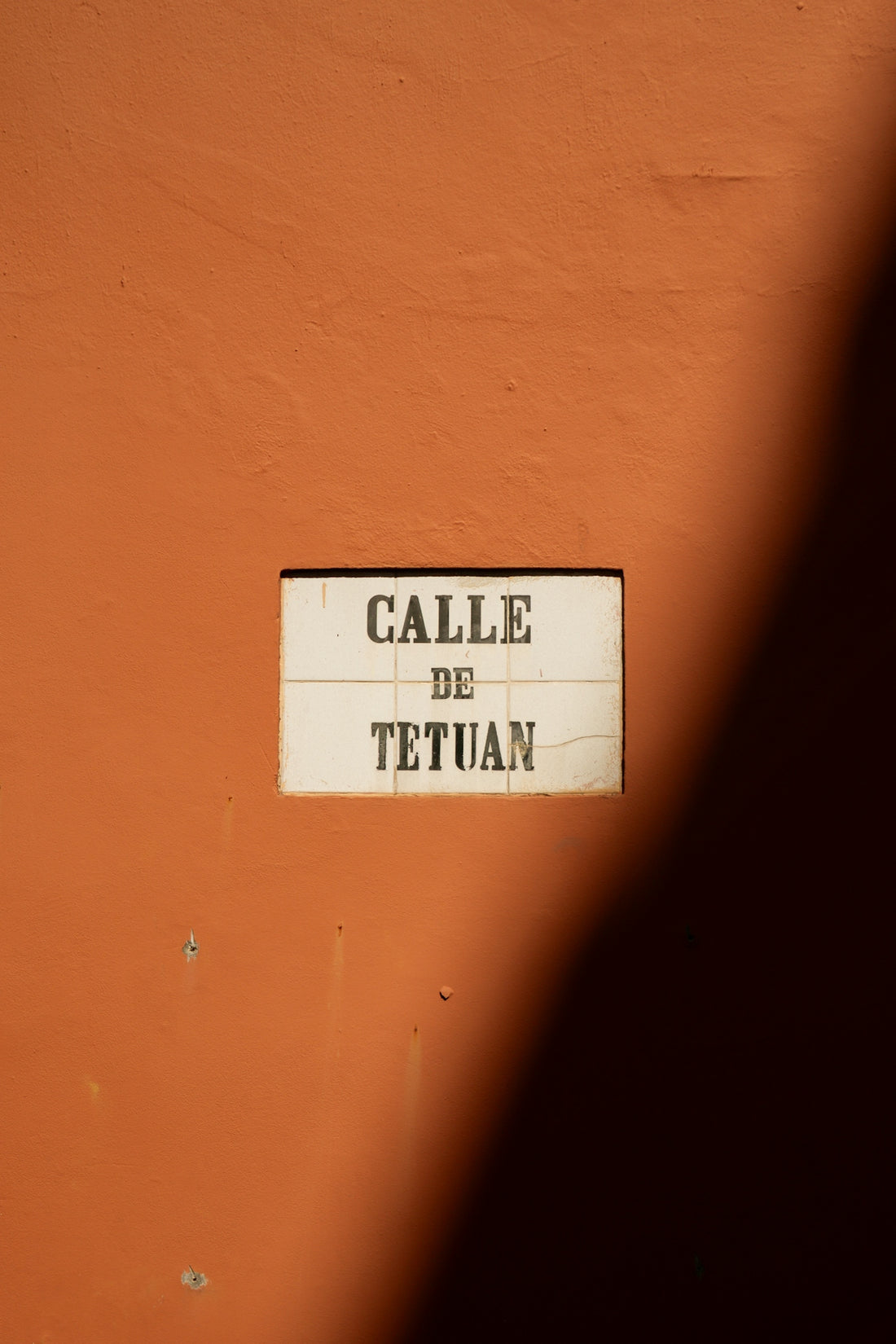 Street sign for calle de tetuan on orange wall