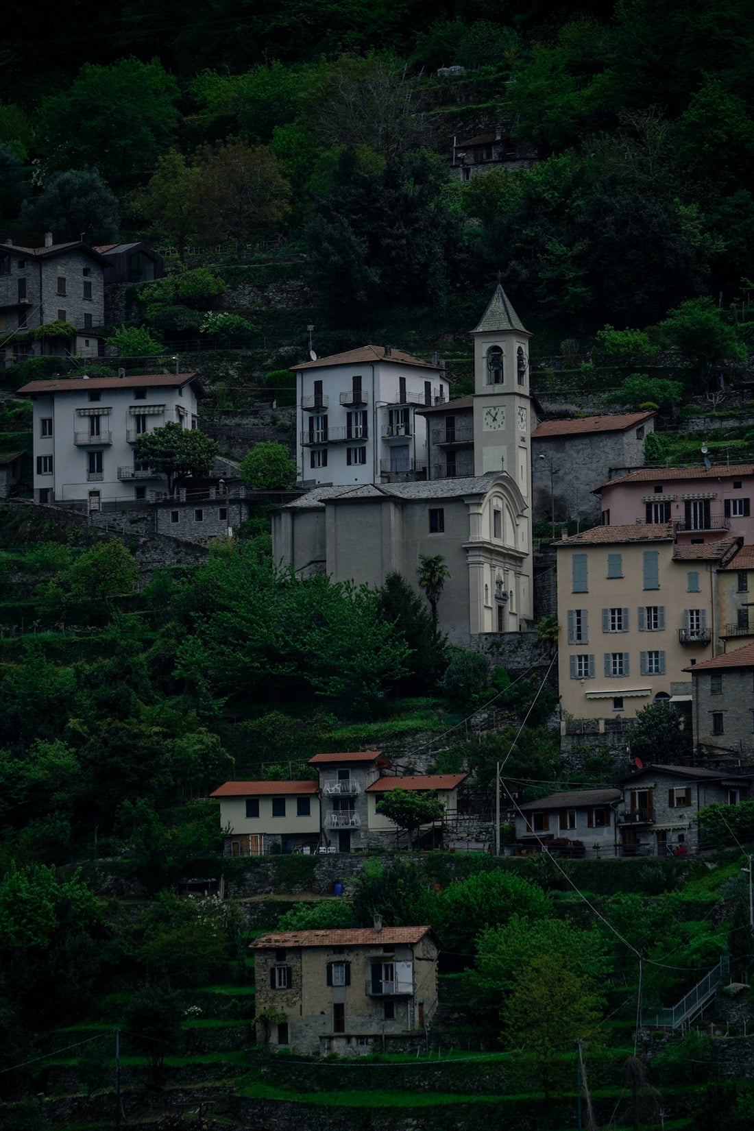 Village nestled on a steep, green mountainside with a church.