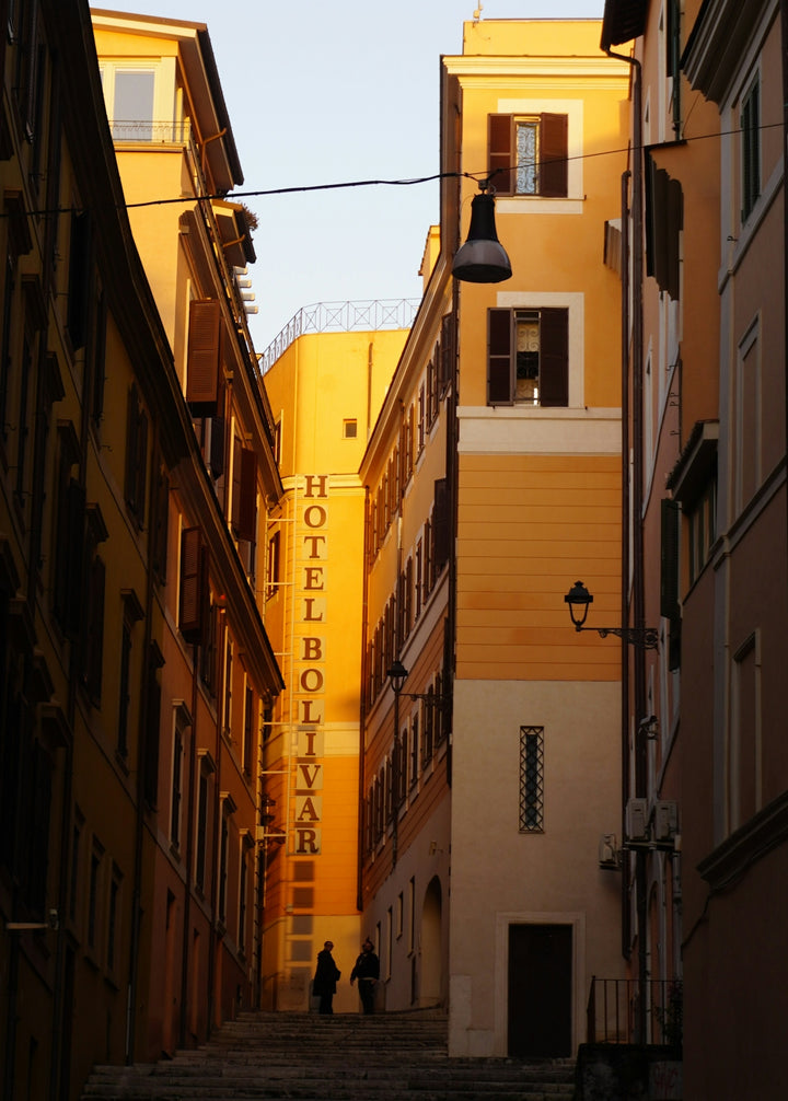 Two people walk up stairs between colorful buildings